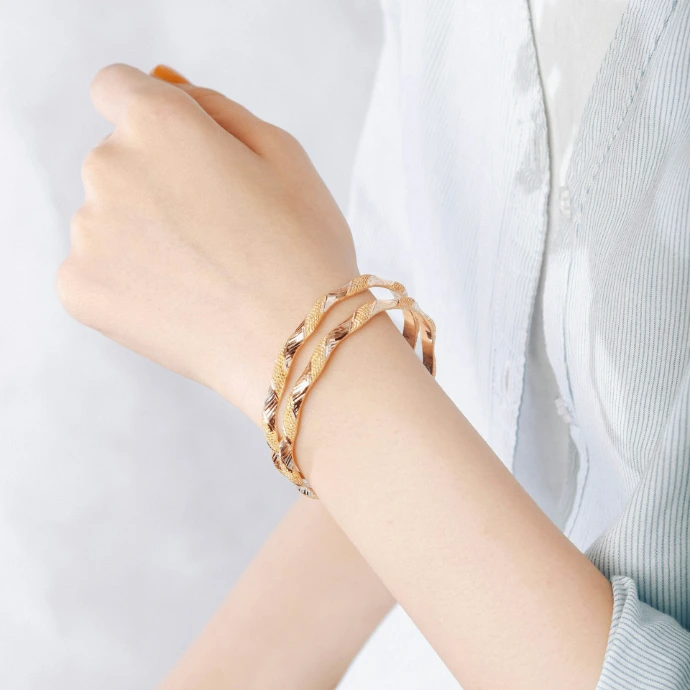 A person wears gold bracelets on wrist