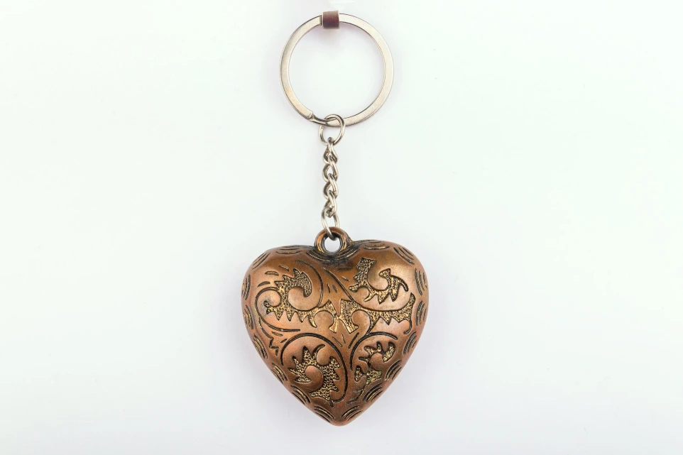 A metal heart shaped keychain hanging from a chain