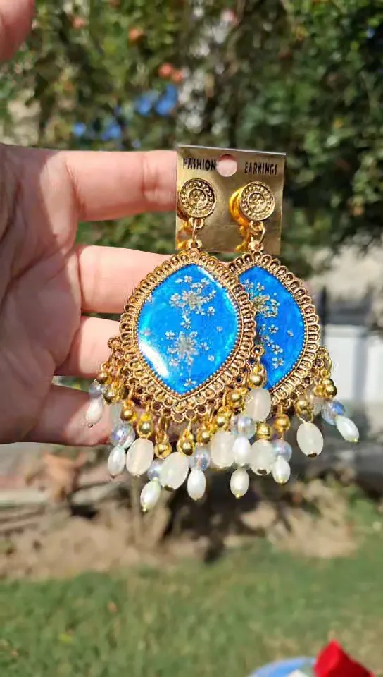Golden framed blue resin earring.